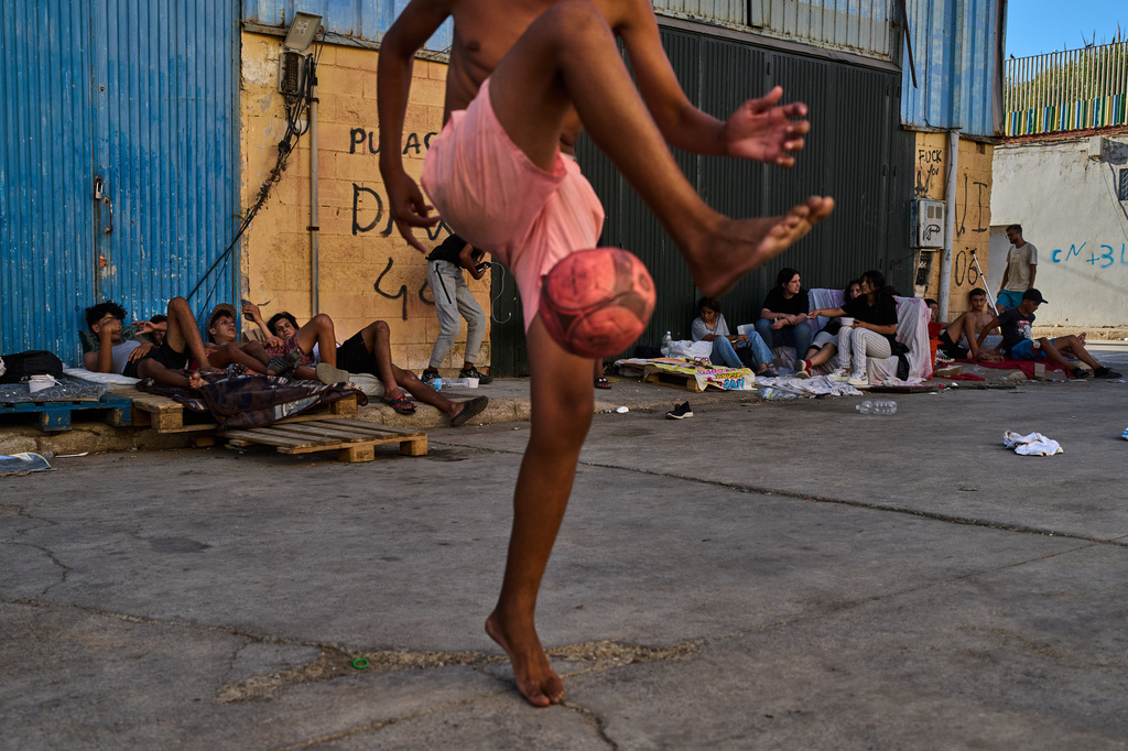Migrants, who crossed from Morocco into Spain, gather in a warehouse area near the Spain-Morocco border in the Spanish enclave of Ceuta, Monday, Aug. 3, 2026. (AP Photo/Bernat Armangue)