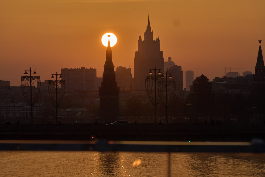The sun is seen behind a Red Star atop of a Kremlin Tower during sunset in Moscow, Thursday, March 12, 2026, backdropped by a Stalin's style skyscraper. (AP Photo/Alexander Zemlianichenko)
