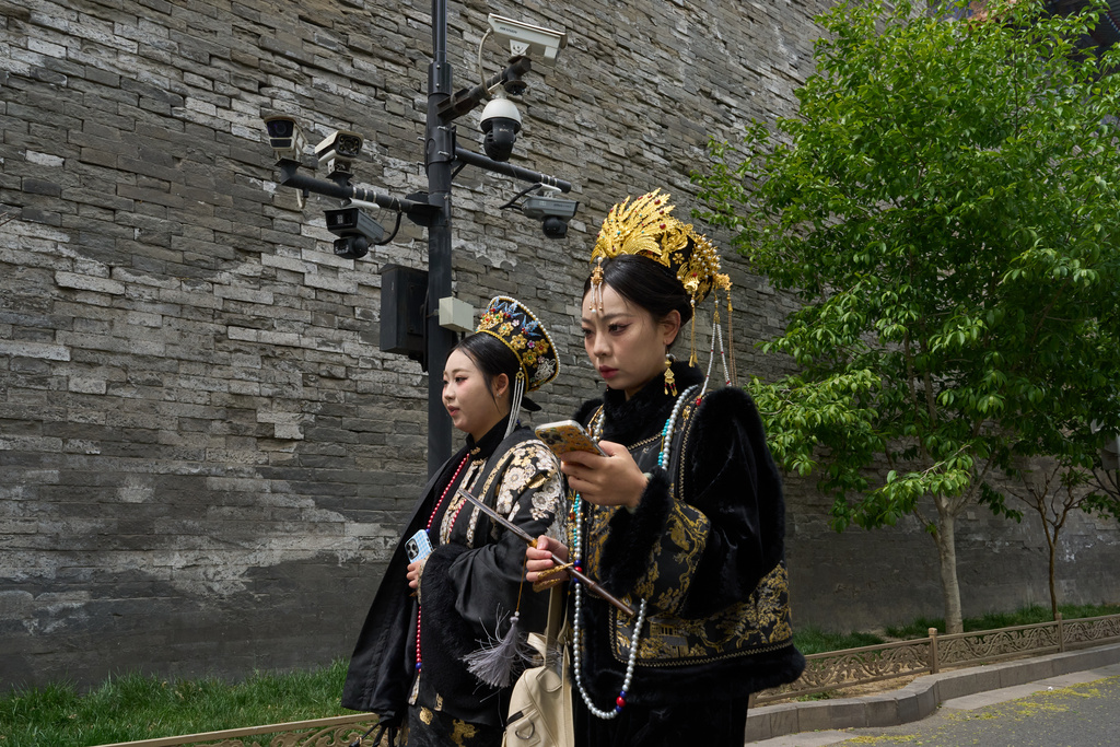 Women in traditional costumes walk past security cameras outside the Forbidden City in Beijing, Saturday, April 12, 2025. (AP Photo/Ng Han Guan)