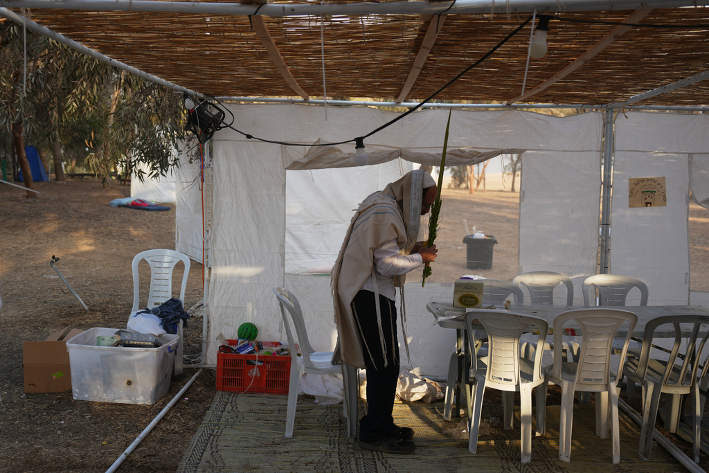 A Jewish man prays during the holiday of Sukkot in an area near the Israeli-Gaza border, in the southern Israel, Thursday, Oct. 9, 2025, after the announcement that Israel and Hamas have agreed to the first phase of a peace plan to pause fighting and release at least some hostages and prisoners. (AP Photo/Ariel Schalit)