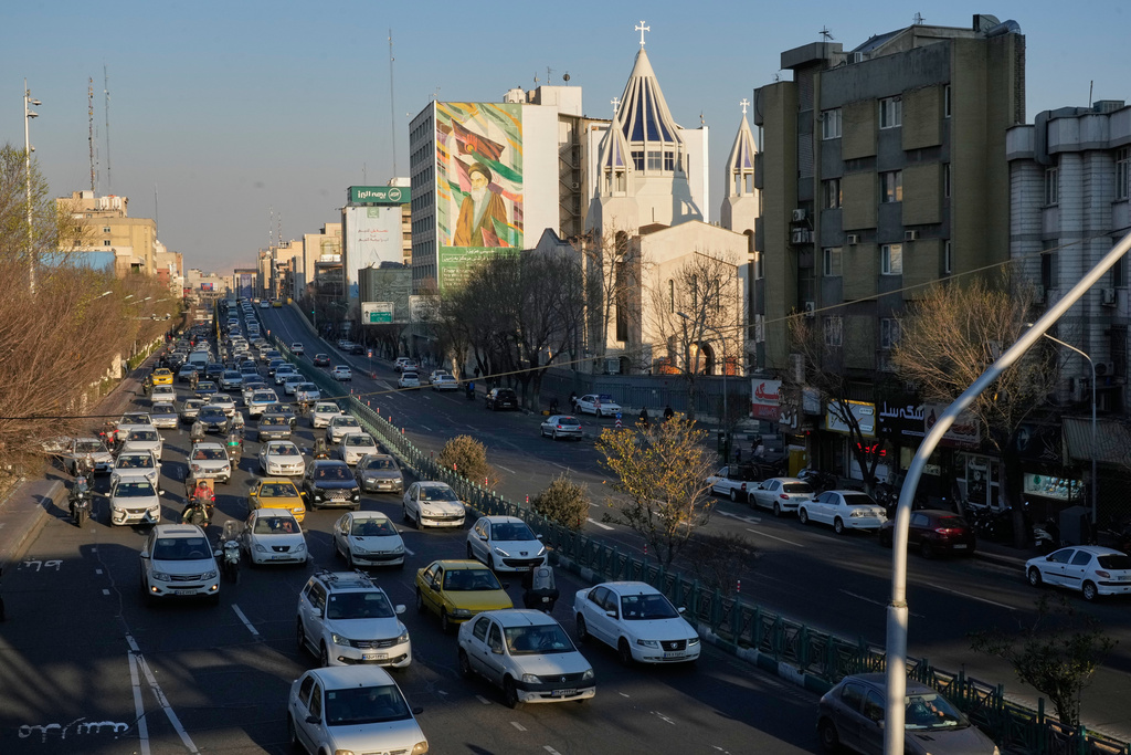 Vehicles drive past the Saint Sarkis church and a painting of the late Iranian revolutionary founder Ayatollah Khomeini in downtown Tehran, Iran, Wednesday, Feb. 25, 2026. (AP Photo/Vahid Salemi)