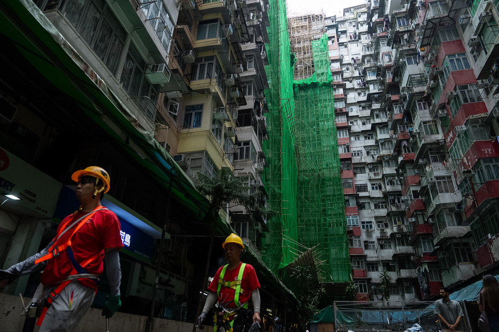 Construction workers walk past a building under renovation in Quarry Bay district after the deadly fire at Wang Fuk Court, in the Tai Po district of Hong Kong's New Territories, Thursday, Dec 4, 2025. (AP Photo/Chan Long Hei)