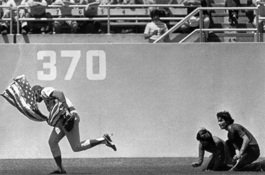 FILE - Outfielder Rick Monday of the Chicago Cubs dashes between two men in the Dodger Stadium Outfield in Los Angeles, in this April 25, 1976 photo, snatching an American flag the men were about to burn. (AP Photo/Los Angeles Herald Examiner, James Roark,File)