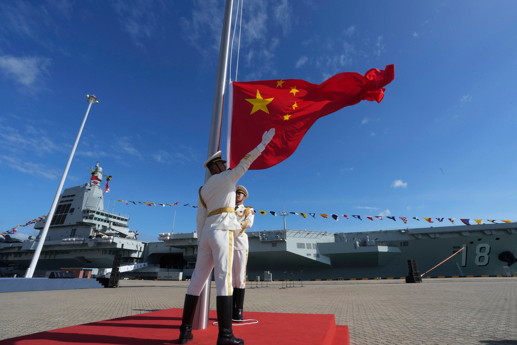 In this photo released by Xinhua News Agency, honor guard members raise the Chinese national flag during a commissioning and flag-presenting ceremony of the Fujian, China's third aircraft carrier and the first that it has both designed and built itself equipped with electromagnetic catapults, at a naval port in Sanya city in southern China's Hainan Province, on Wednesday, Nov. 5, 2025. (Li Gang/Xinhua via AP)