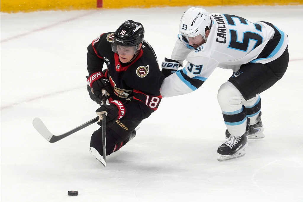 Utah Mammoth left wing Michael Carcone (53) brings down tOttawa Senators centre Tim Stutzle (18) during third period NHL action, in Ottawa, Sunday, Nov. 9, 2025. (Adrian Wyld/The Canadian Press via AP)