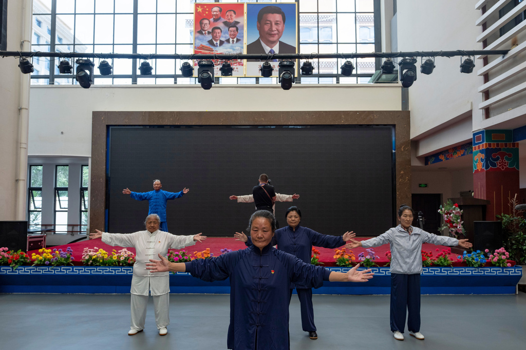 Elderly residents perform tai chi near the portrait of Chinese President Xi Jinping and other Chinese leaders at the Chengguan District Day Care Center for the Elderly in western China's Tibet autonomous region on July 20, 2026, as seen during a government-organized visit for foreign journalists. (AP Photo/Ng Han Guan)