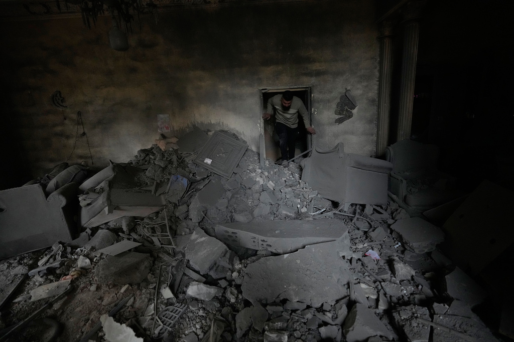 A man checks his damaged apartment at the site of a destroyed building that was hit in an Israeli airstrike in the southern port city of Tyre, Lebanon, Thursday, March 26, 2026. (AP Photo/Hussein Malla)