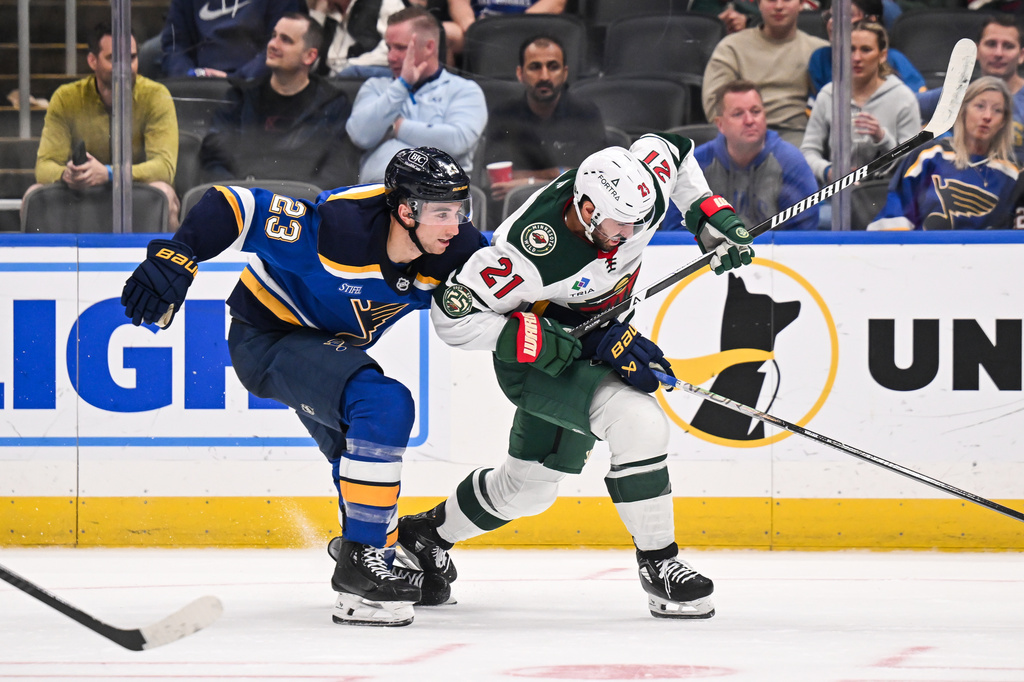 St. Louis Blues' Logan Mailloux (23) skates against Minnesota Wild's Robby Fabbri (21) during the third period of an NHL hockey game Monday, April 13, 2026, in St. Louis. (AP Photo/Connor Hamilton)