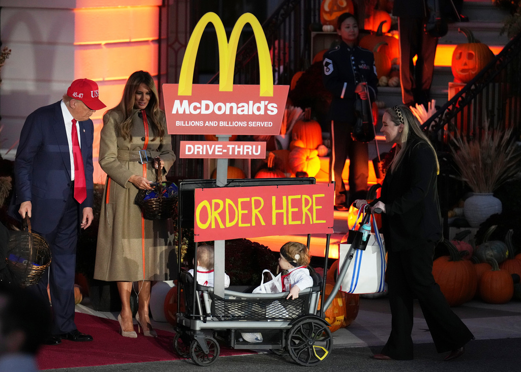 President Donald Trump, from left, and first lady Melania Trump hand out candy and greet a family dressed as employees of a McDonald's Drive-Thur during a Halloween event on the South Lawn of the White House, Thursday, Oct. 30, 2025, in Washington. (AP Photo/Jacquelyn Martin)
