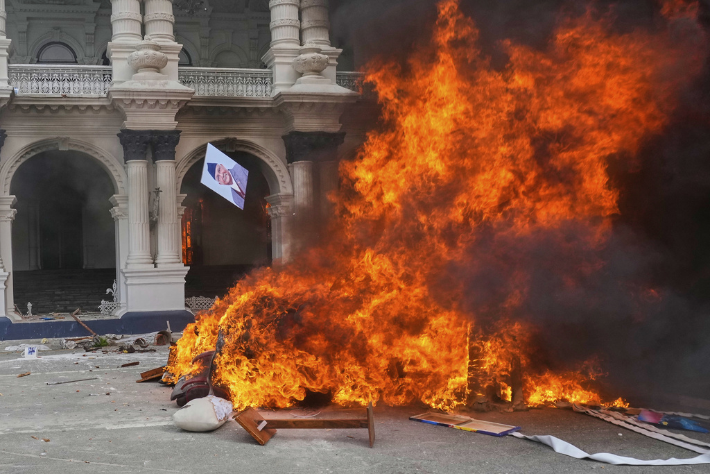 A protester throws a photograph of Nepal Prime Minister Khadga Prasad Oli in the fire at the Singha Durbar, the seat of Nepal's government's various ministries and offices during a protest against social media ban and corruption in Kathmandu, Nepal, Tuesday, Sept. 9, 2025. (AP Photo/Niranjan Shrestha)
