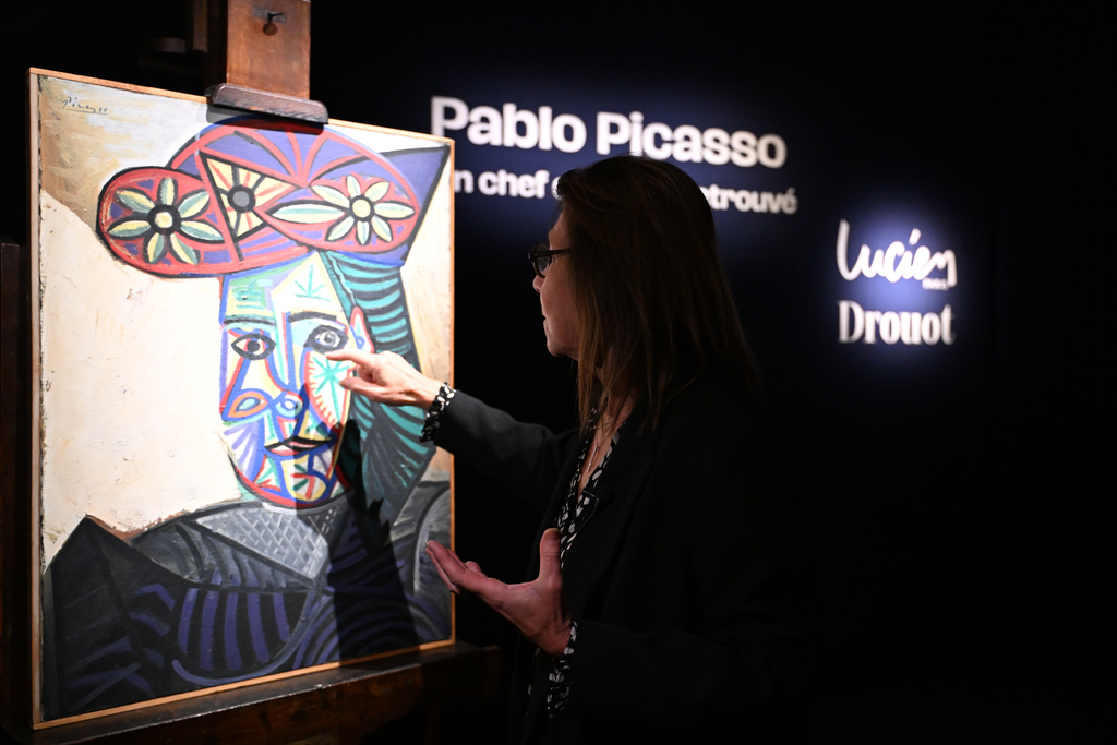 Art expert Agnes Sevestre-Barbe points to a rediscovered Picasso painting "Bust of a Woman in a Flowery Hat", Wednesday, Oct. 22, 2025 in Paris. The portrait painted in 1943 will be sold at auction Friday in Paris, was bought in 1944 and shows his partner Dora Maar. (AP Photo/Emma Da Silva)
