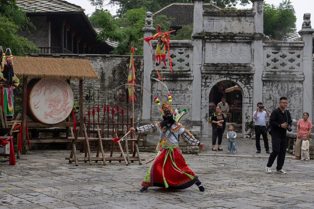 A Dixi opera performer entertains people at Tianlong Tunpu, an ancient town in southwestern China's Guizhou province on Thursday, May 28, 2026. (AP Photo/Ng Han Guan)