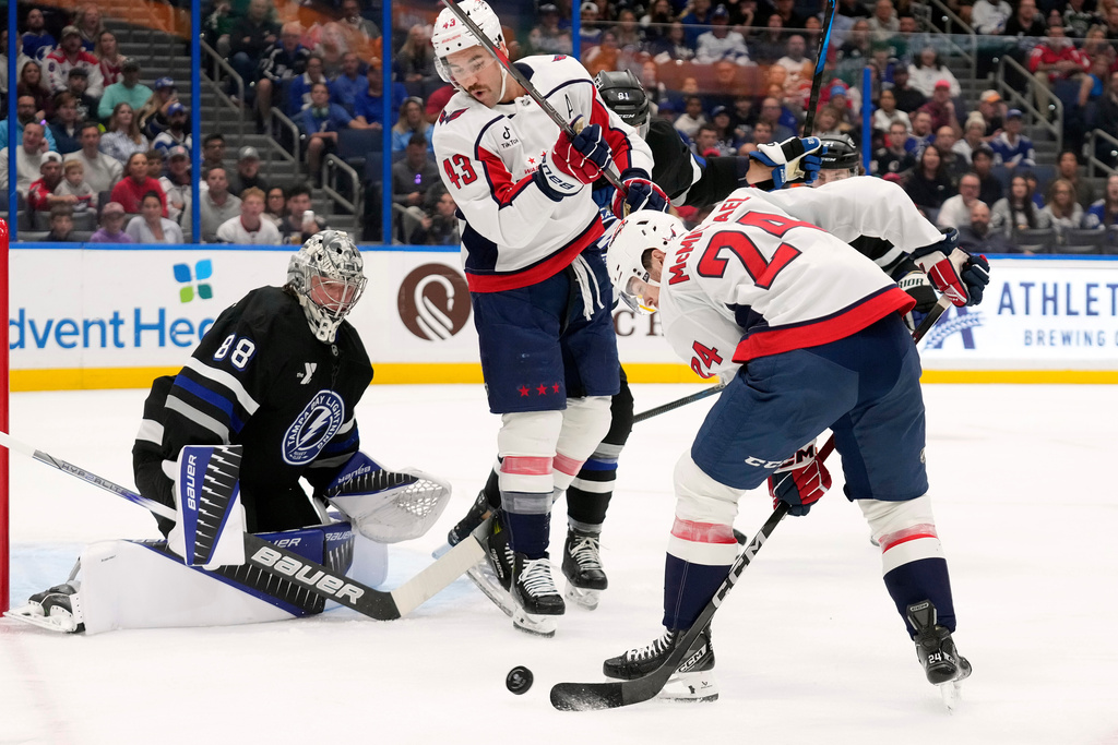Washington Capitals center Connor McMichael (24) shoots between his legs on Tampa Bay Lightning goaltender Andrei Vasilevskiy (88) during the first period of an NHL hockey game Saturday, Nov. 8, 2025, in Tampa, Fla. (AP Photo/Chris O'Meara)