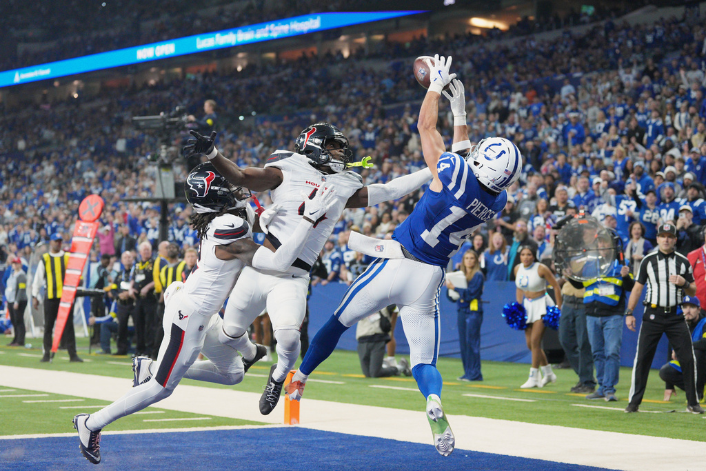 Indianapolis Colts wide receiver Alec Pierce (14) catches a touchdown pass as Houston Texans' Kamari Lassiter (4) and Calen Bullock defend during the first half of an NFL football game Sunday, Nov. 30, 2025, in Indianapolis. (AP Photo/AJ Mast)