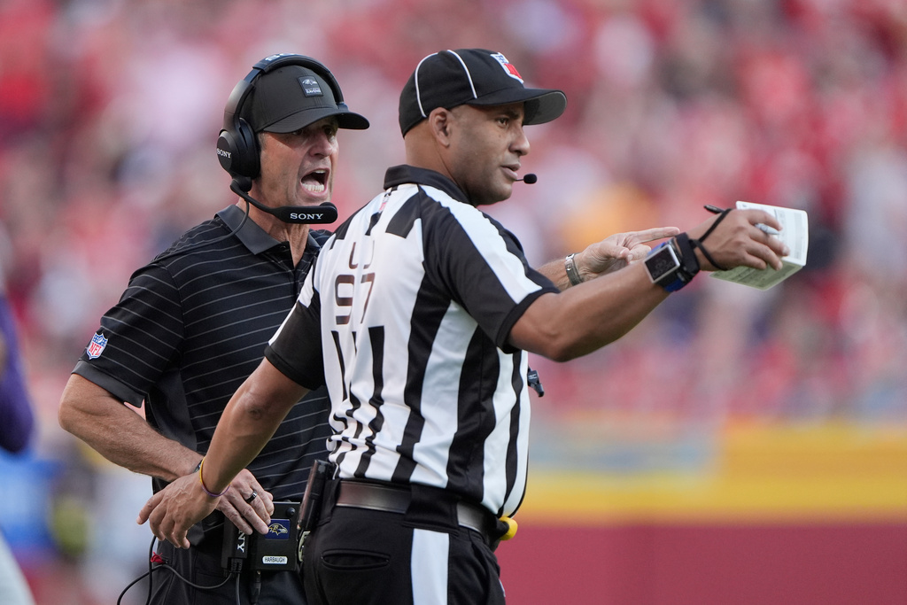 Baltimore Ravens head coach Jim Harbaugh, left, talks on the sideline with line judge Brian Perry (97) during the second half of an NFL football game against the Kansas City Chiefs Sunday, Sept. 28, 2025, in Kansas City, Mo. (AP Photo/Charlie Riedel)