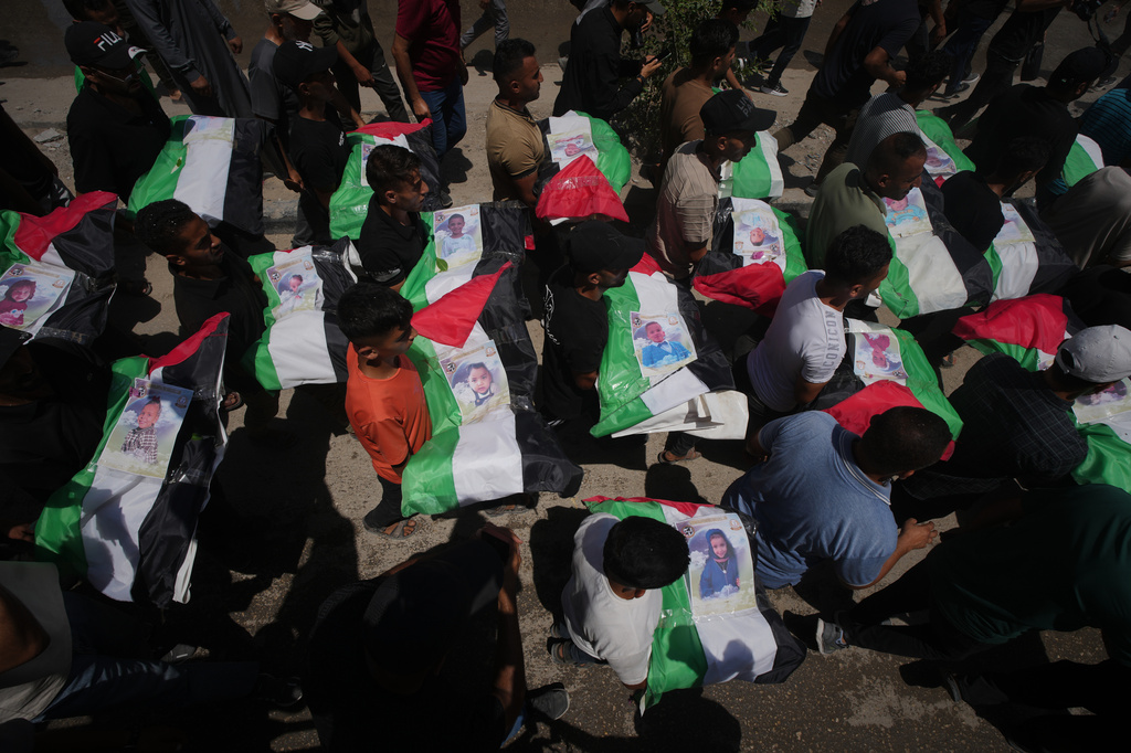 Palestinians carry the flag-draped bodies of members of the Hassayna and Abu Sharia families, who were killed in an Israeli strike in 2023 and whose remains were recently recovered from the rubble, during their funeral in Gaza City, Tuesday, Aug. 4, 2026. (AP Photo/Jehad Alshrafi)