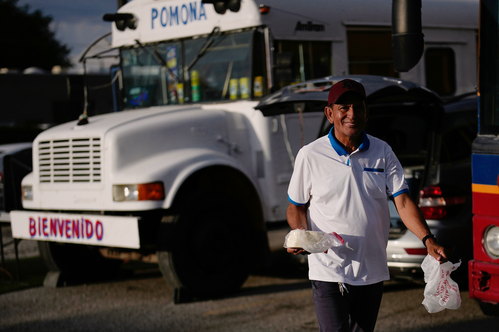 Jadiel Rodriguez, a Venezuelan immigrant, carries food along a row of food trucks on Wednesday, July 15, 2026, in Midvale, Utah. (AP Photo/Gregory Bull)
