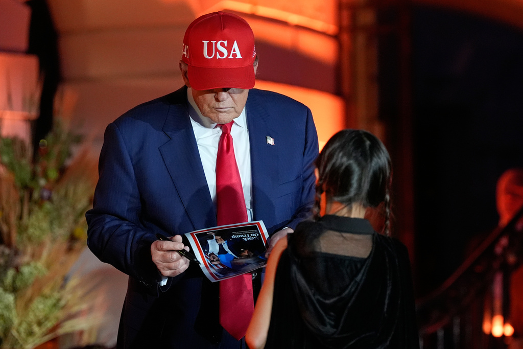 President Donald Trump signs a autograph during a Halloween at the White House event on the South Lawn, Thursday, Oct. 30, 2025, in Washington. (AP Photo/Alex Brandon)
