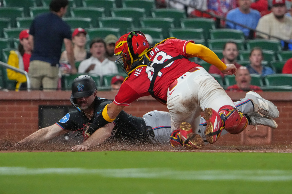 Miami Marlins' Graham Pauley, left, scores ahead of the tag from St. Louis Cardinals catcher Iván Herrera during the eighth inning of a baseball game Friday, June 26, 2026, in St. Louis. (AP Photo/Jeff Roberson)