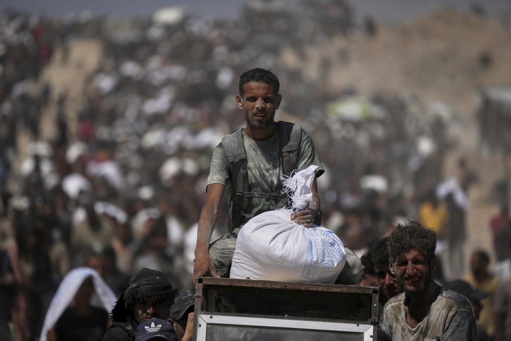 Palestinians carry sacks of flour taken from a humanitarian aid convoy in the outskirts of Beit Lahiya, northern Gaza Strip, Aug. 1, 2025. (AP Photo/Jehad Alshrafi)