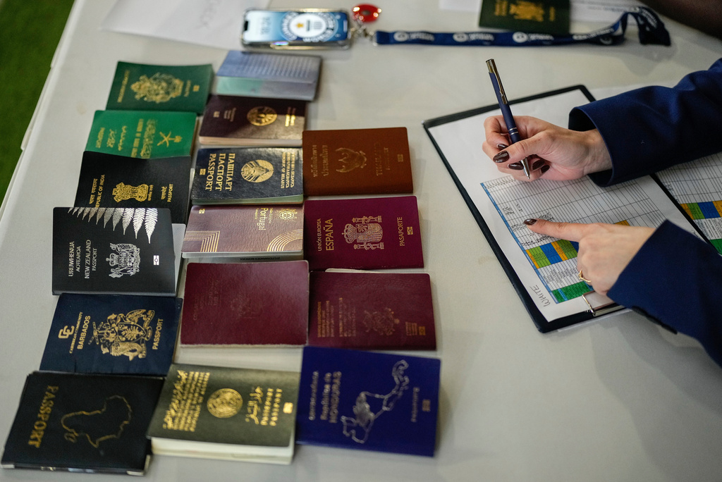 Passports of participants are placed on a table as Joanne Brent, Guiness World Records adjudicator, monitors an exhibition soccer match organised by FIFA attempting to break the Guinness World Record for most nationalities in a match, in Rabat, Morocco, Wednesday, Nov. 5, 2025. (AP Photo/Mosa'ab Elshamy)