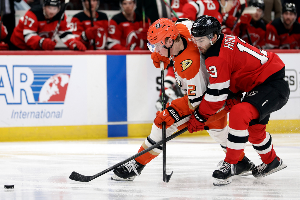Anaheim Ducks defenseman Jackson Lacombe (2) battles for the puck with New Jersey Devils center Nico Hischier (13) during the second period of an NHL hockey game Saturday, Dec. 13, 2025, in Newark, N.J. (AP Photo/Adam Hunger)