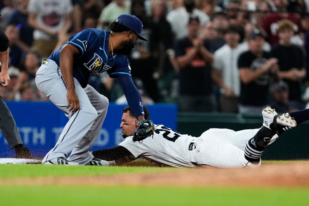 Detroit Tigers' Javier Báez slides safely into third base for a triple ahead of the tag of Tampa Bay Rays third baseman Junior Caminero during the seventh inning of a baseball game Tuesday, Aug. 25, 2026, in Detroit. (AP Photo/Paul Sancya)