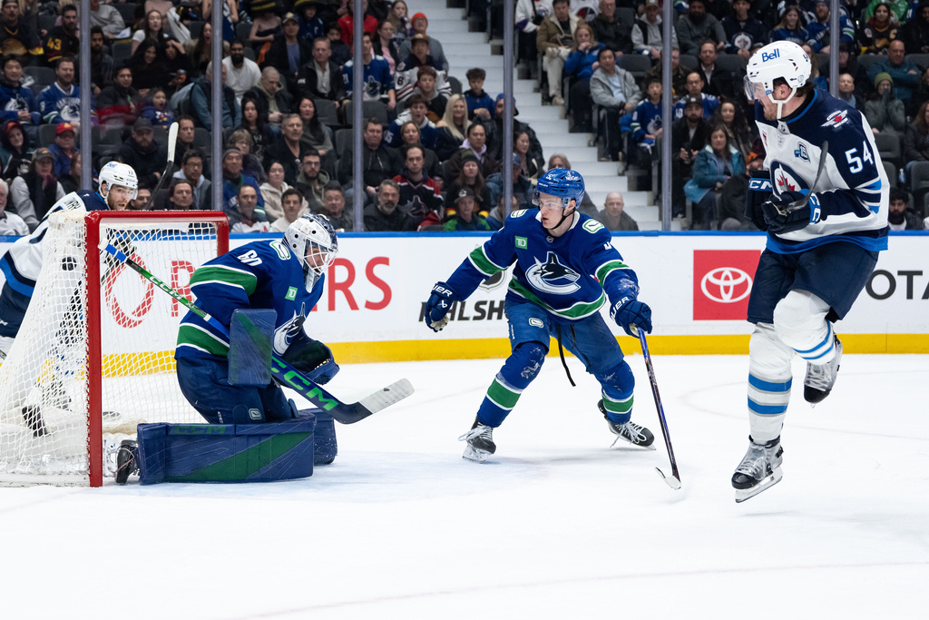 Winnipeg Jets' Cole Perfetti, not seen, scores on Vancouver Canucks goaltender Nikita Tolopilo (60) as Tom Willander (5) and Winnipeg's Dylan Samberg (54) watch during an overtime NHL hockey game in Vancouver, B.C., on Wednesday, Feb. 25, 2026. (Ethan Cairns/The Canadian Press via AP)