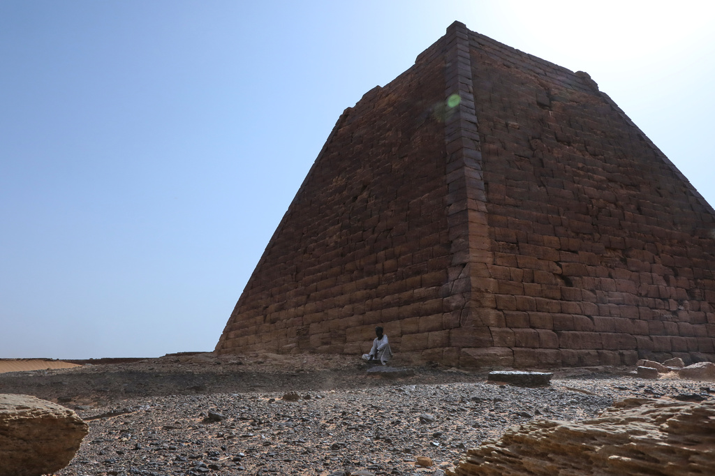 A man sits beside a pyramid at the Meroe archaeological site in Bejrawiya, Sudan, Saturday, Aug. 1, 2026. (AP Photo/Mohnd Blal)