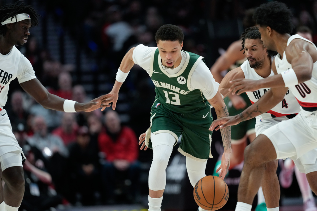 Milwaukee Bucks guard Ryan Rollins (13) goes for the ball surrounded by Portland Trail Blazers players during the first half of an NBA basketball game Wednesday, March 25, 2026, in Portland, Ore. (AP Photo/Jenny Kane)