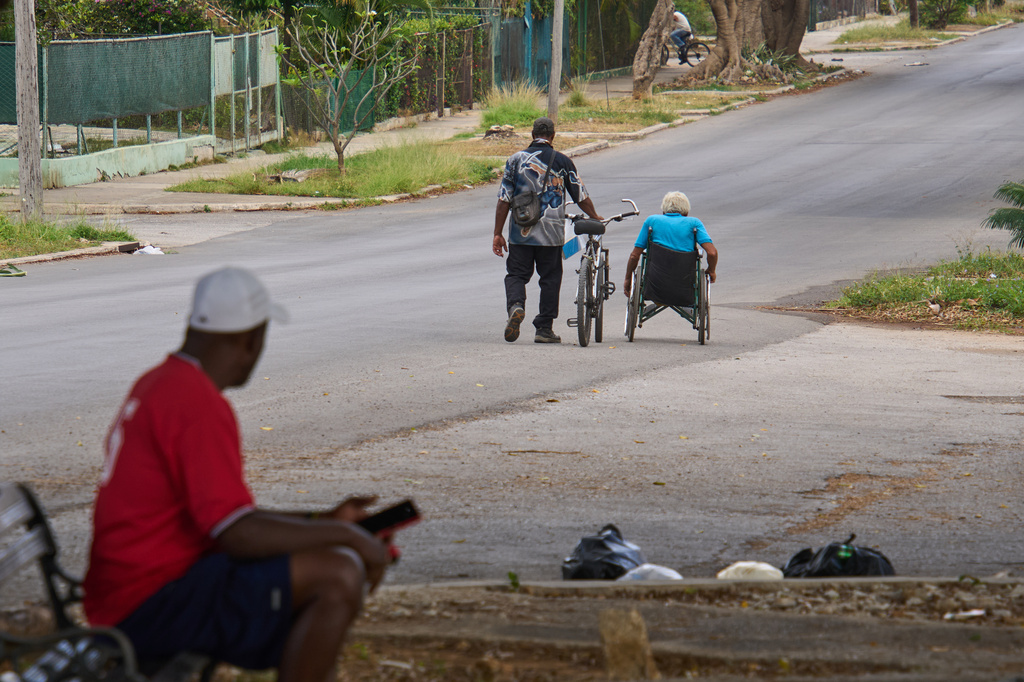 An elderly man makes his way in his wheelchair while a friend walks a bicycle beside him, in Havana, Cuba, Wednesday, April 15, 2026. (AP Photo/Ramon Espinosa)