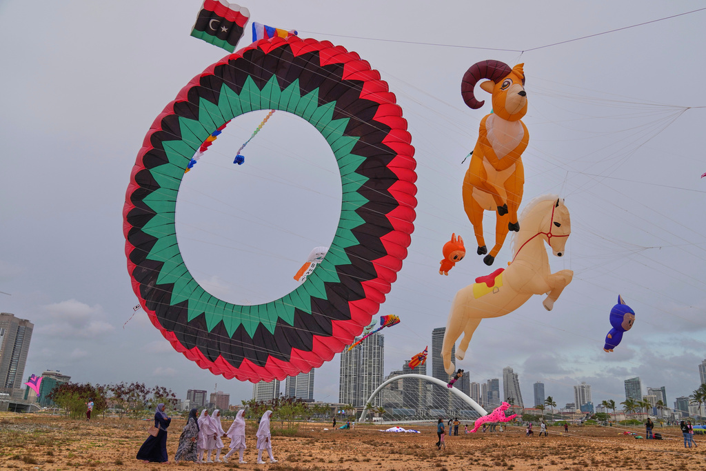 Sri Lankan girls walk past kites of different shapes and sizes at the Colombo International Kite Festival in Colombo, Sri Lanka, Saturday, Aug. 23, 2025. (AP Photo/Eranga Jayawardena)