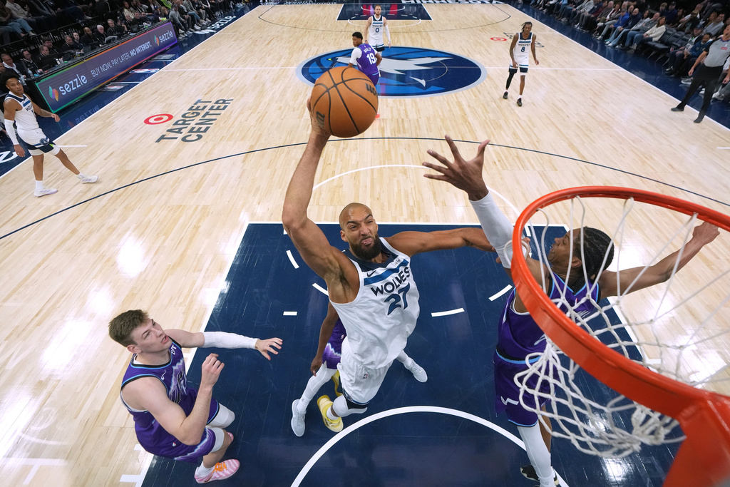 Minnesota Timberwolves center Rudy Gobert (27) dunks while defended by Utah Jazz forwards Kyle Filipowski (22), left, and Cody Williams (5), right, during the first half of an NBA basketball game, Wednesday, March 18, 2026, in Minneapolis. (AP Photo/Abbie Parr)