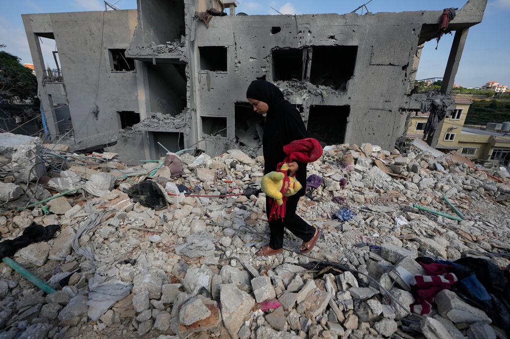 A resident carries belongings as she walks through the rubble of her home destroyed in an Israeli airstrike a day earlier in the southern village of Maarakeh, Lebanon, Wednesday, May 27, 2026. (AP Photo/Mohammed Zaatari)