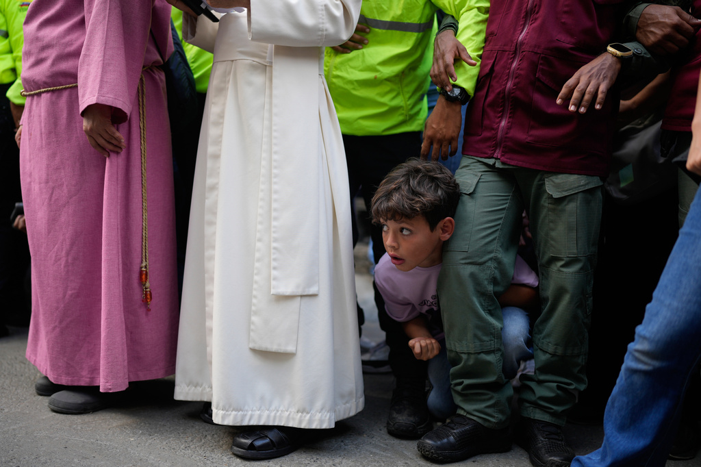 A boy watches a Way of the Cross reenactment as part of Holy Week celebrations in the Petare neighborhood of Caracas, Venezuela, Friday, April 3, 2026. (AP Photo/Ariana Cubillos)