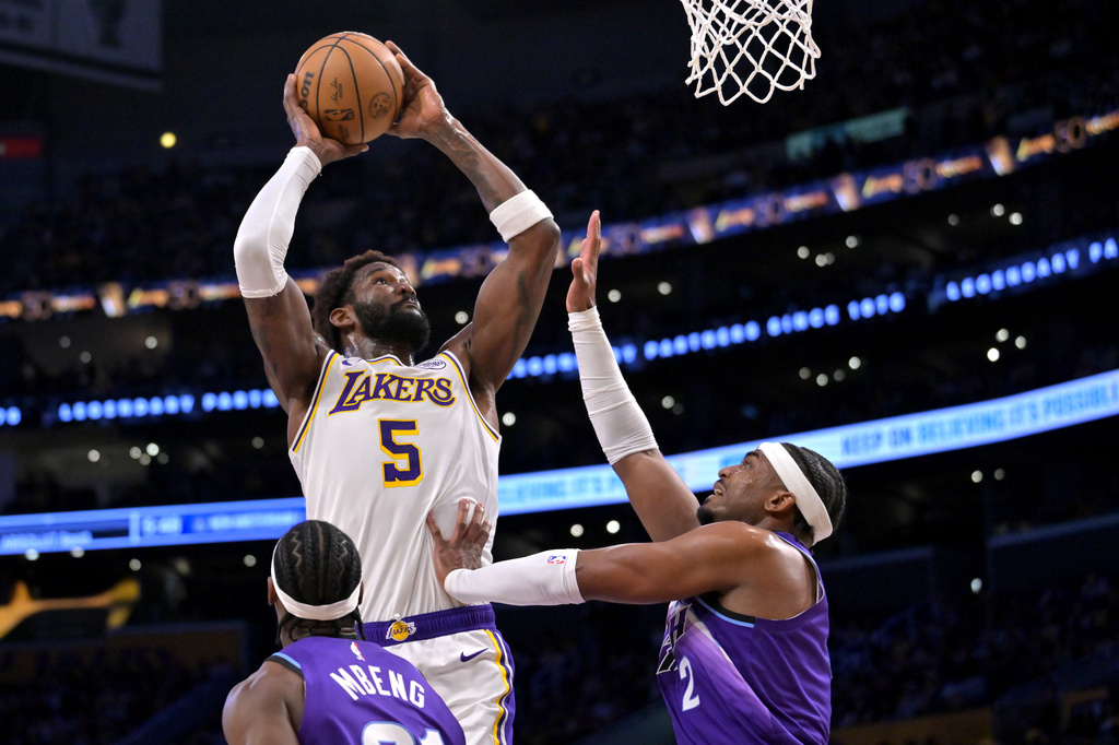 Los Angeles Lakers center Deandre Ayton (5) goes up to dunk as he is defended by Utah Jaz guard Bez Mbeng, bottom left, and forward Blake Hinson, right, during the first half of an NBA basketball game Sunday, April 12, 2026, in Los Angeles. (AP Photo/Jayne Kamin-Oncea)