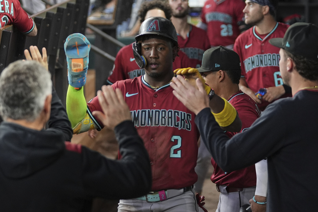 Arizona Diamondbacks' Geraldo Perdomo celebrates with the team after scoring on a Ketel Marte single in the third inning of a baseball game against the Texas Rangers Wednesday, Aug. 13, 2025, in Arlington, Texas. (AP Photo/Tony Gutierrez)