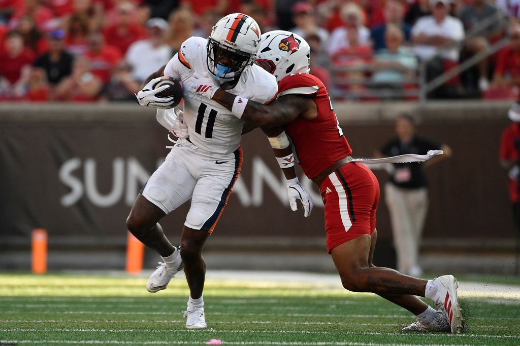 Louisville Cardinals defensive back JoJo Evans Jr. (27) attempts to bring down Virginia wide receiver Trell Harris (11) during the second half of an NCAA college football game in Louisville, Ky., Saturday, Oct. 4, 2025. (AP Photo/Timothy D. Easley)