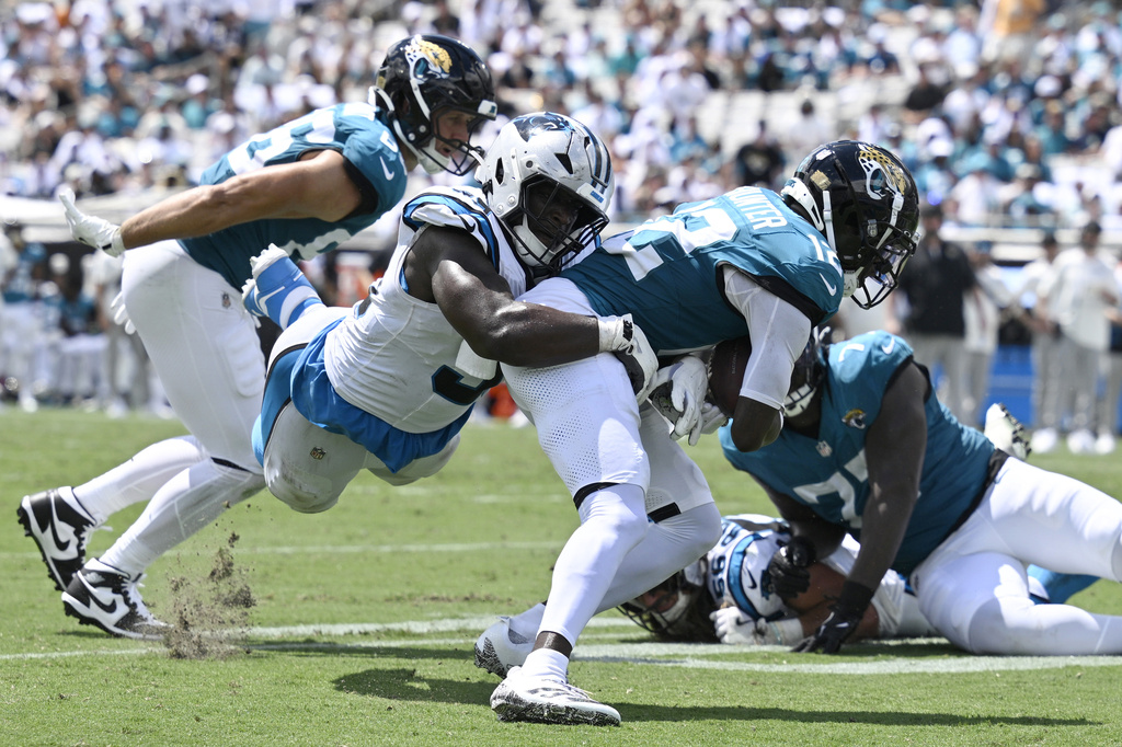 Carolina Panthers defensive tackle Tershawn Wharton (92) tackles Jacksonville Jaguars wide receiver Travis Hunter (12) during the first half of an NFL football game, Sunday, Sept. 7, 2025, in Jacksonville, Fla. (AP Photo/Phelan M. Ebenhack)