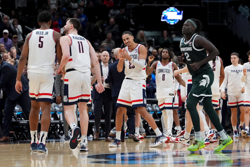 UConn forward Jayden Ross (23) celebrates with forward Tarris Reed Jr. (5) and forward Alex Karaban (11) against Michigan State during the second half in the Sweet 16 of the NCAA college basketball tournament, Saturday, March 28, 2026, in Washington. (AP Photo/Stephanie Scarbrough)