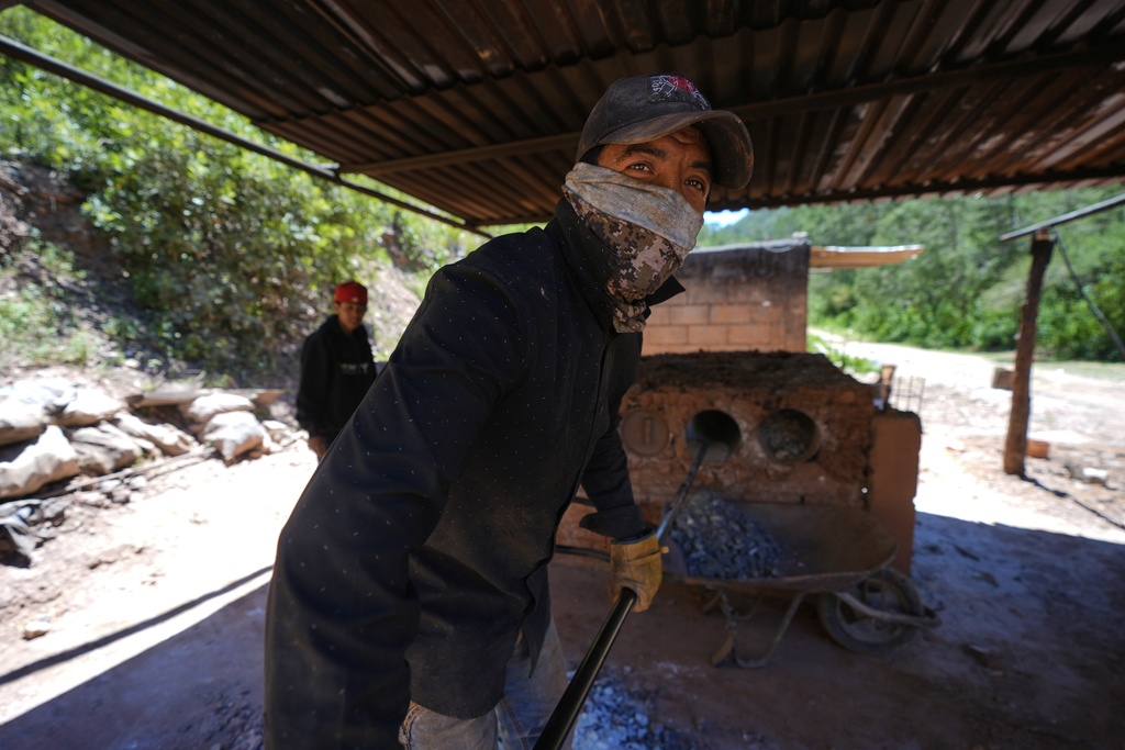 Carlos Martinez removes mercury rocks from furnace tubes after baking them in San Joaquin, Mexico, Tuesday, Aug. 19, 2025. (AP Photo/Fernando Llano)