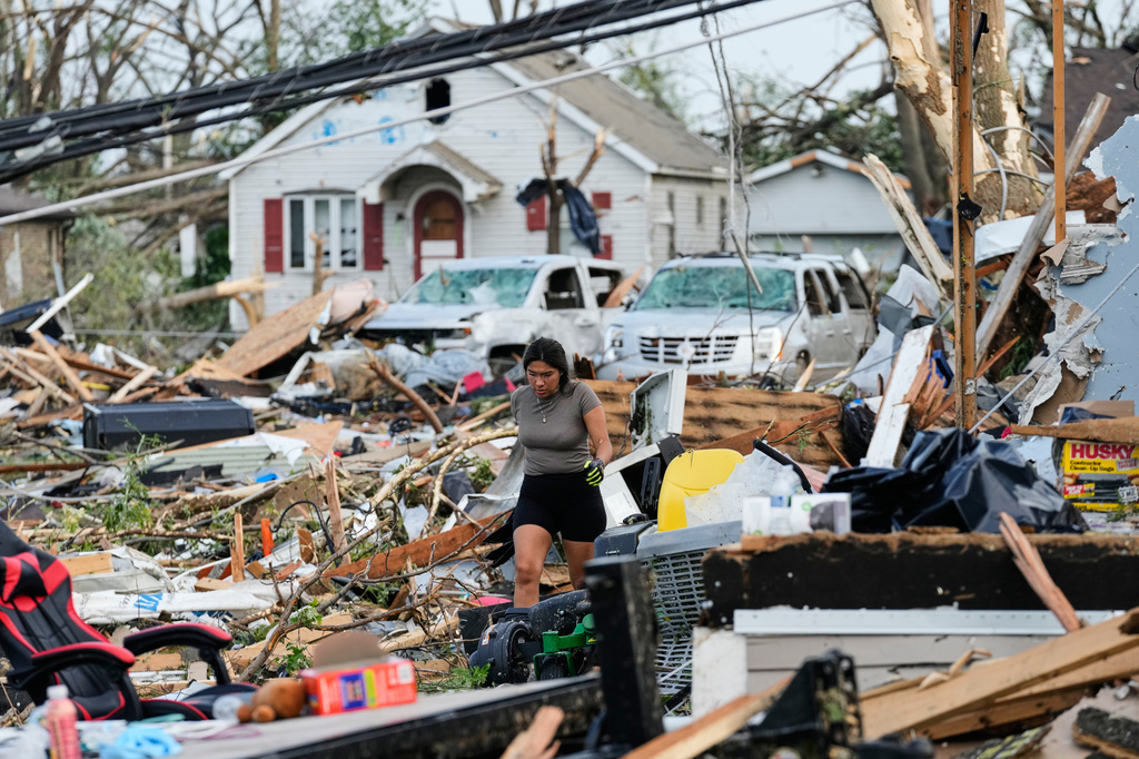 A woman walks among debris after a tornado struck Monday, July 27, 2026, in Menasha, Wis. (AP Photo/Kayla Wolf)