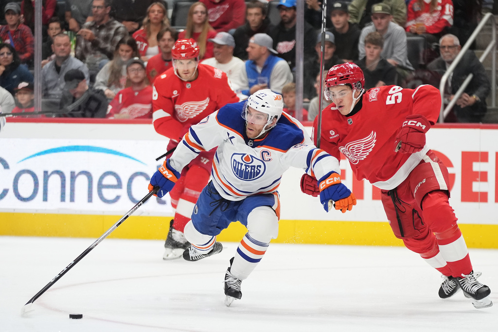 Edmonton Oilers center Connor McDavid, front left, and Detroit Red Wings center Emmitt Finnie, right, vie for the puck during the first period of an NHL hockey game Sunday, Oct. 19, 2025, in Detroit. (AP Photo/Ryan Sun)