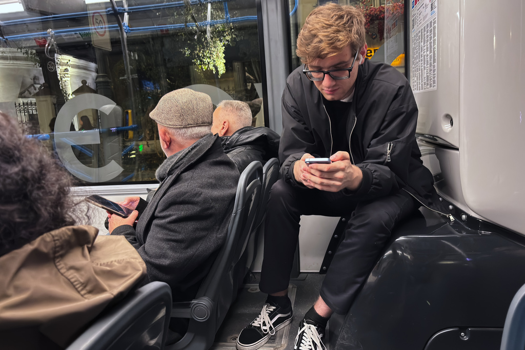 FILE - Passengers look at their smartphones on a bus in Moscow, Oct. 23, 2025. (AP Photo/Alexander Zemlianichenko, File)