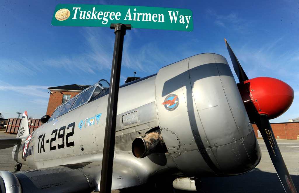 FILE - The Tuskegee Airmen Way street sign is briefly displayed in front of a 1943 North American T6 Texan aircraft used to train pilots during WWII, at the Selfridge Air National Guard Base, in Harrison Township, Mich., Feb. 27, 2018. (Todd McInturf/Detroit News via AP, File)