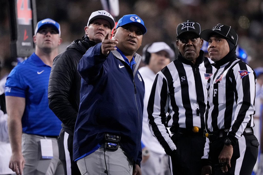 BYU head coach Kalani Sitake, center, looks to a replay with officials during the first half of an NCAA college football game against Cincinnati, Saturday, Nov. 22, 2025, in Cincinnati. (AP Photo/Carolyn Kaster)