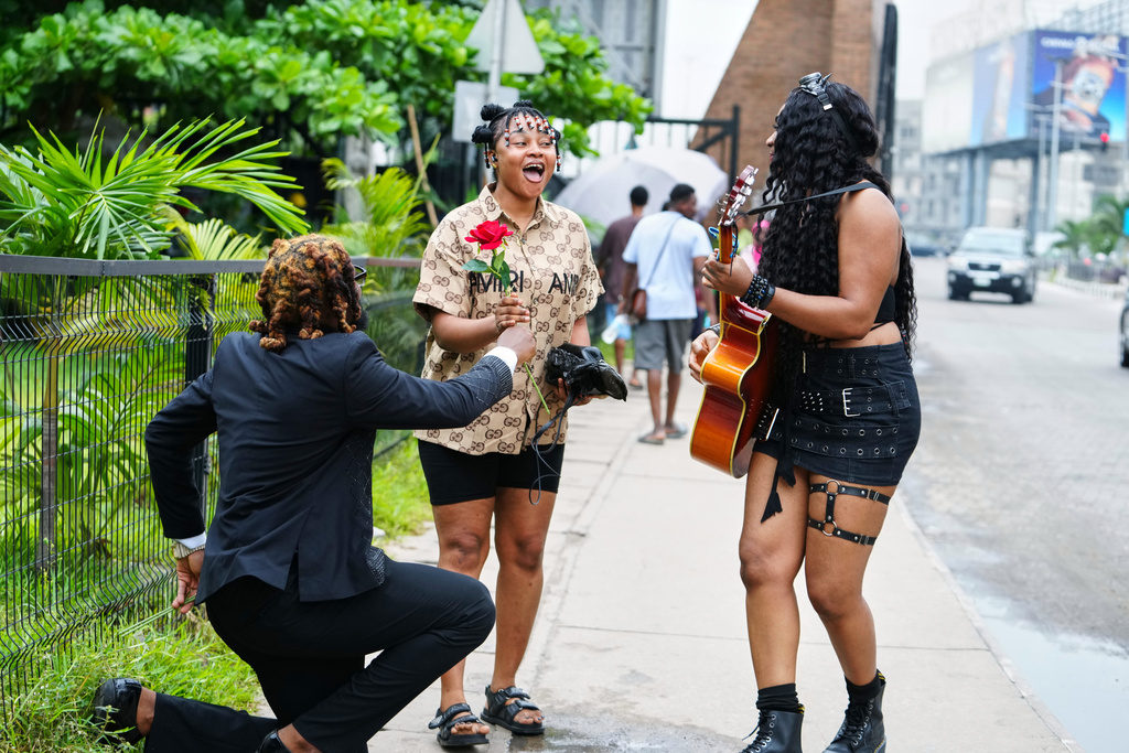 Nigerian rock musician Bianca "Clayrocksu" Okorocha, right, accompanied by Daniel Onyemachi-Chiweolu, popularly known as Machigold, left, gives single-stem roses crooning love songs to commuters ahead of Valentine's Day in Lagos, Nigeria, Tuesday, Feb.10, 2026. (AP Photo/Sunday Alamba)