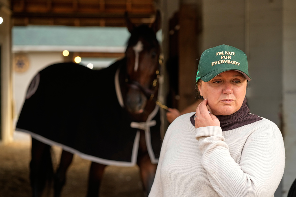 FILE - Trainer Cherie DeVaux stands watches from a barn after a workout at Churchill Downs on April 27, 2026, in Louisville, Ky. (AP Photo/Charlie Riedel, File)
