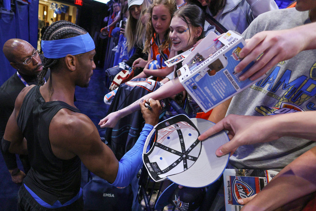 Oklahoma City Thunder guard Shai Gilgeous-Alexander, bottom left, gives autographs to fans before Game 1 of a first-round NBA playoffs basketball series against the Phoenix Suns, Sunday, April 19, 2026, in Oklahoma City. (AP Photo/Nate Billings)