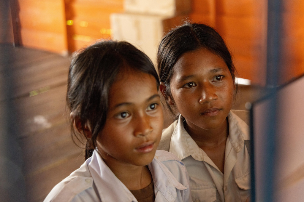 Thirteen-year-old Sou Sreynich, right, attends a computer class at a school in one of the floating villages of Cambodia's Tonle Sap Lake on Monday, June 29, 2026. (AP Photo/Anton L. Delgado)
